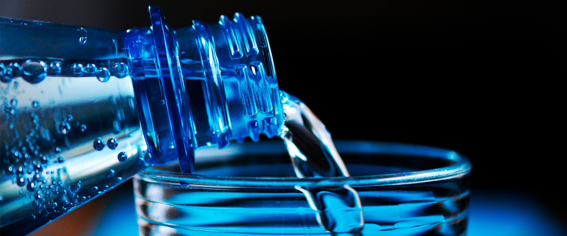 L'eau minérale est versée à partir d'une bouteille en verre PET